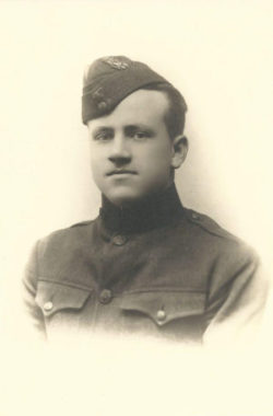 Photo, head and shoulders of a young man in uniform looking into the camera.