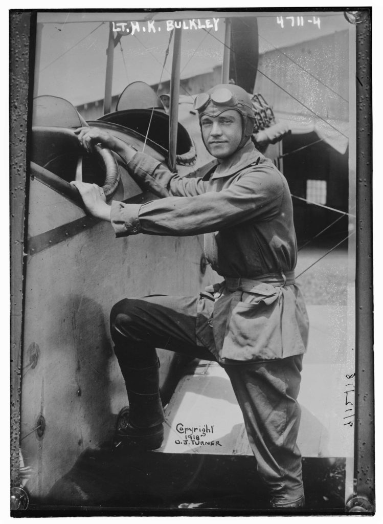 Photo of a man in a flying suit with goggles on his forehead apparently getting ready to climb into a two-seater plane. At the top is written "Lt. H. K. Bulkley." Towards the bottom is written "Copyright 1918 O. J. Turner."