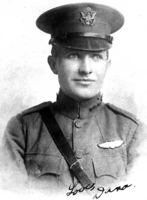 Formal photo of head and bust of a young man in uniform with a peaked cap, Sam Browne belt, and wings over his left breast pocket.