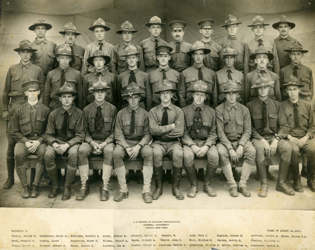Photo of twenty-eight men in three rows in uniform and wearing, with a few exceptions, campaign hats.