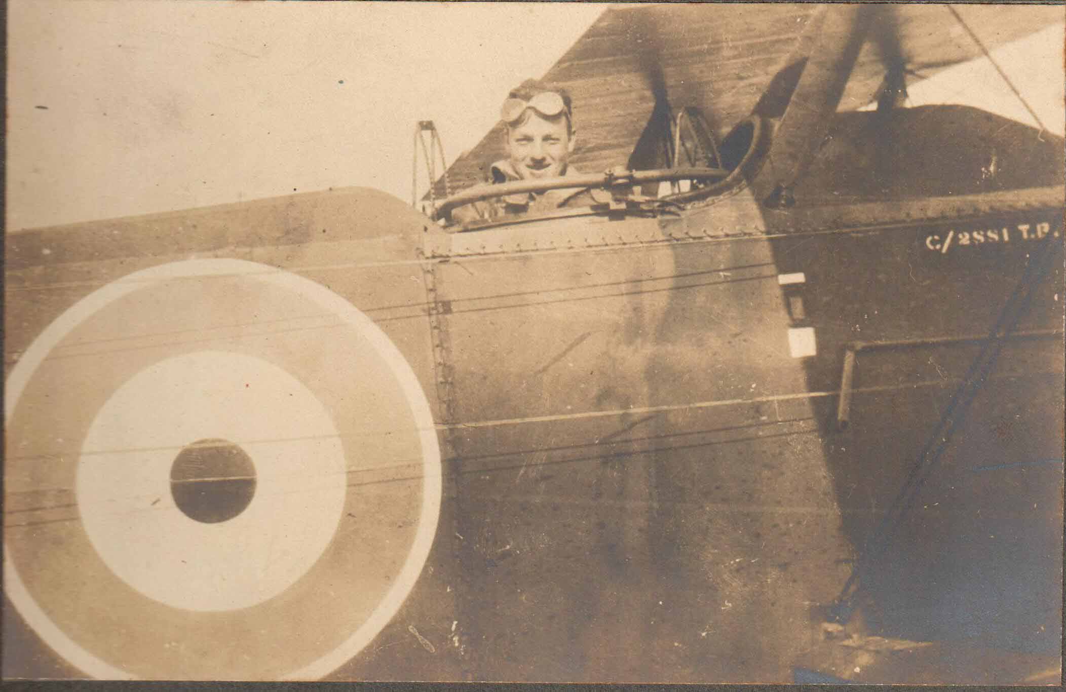 Close up photo of a plane with a man's head visible in the cockpit.