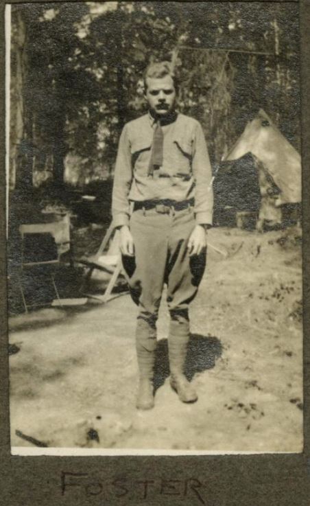 A photo labelled "Foster" pasted into an album showing a mustached man standing before a tent.