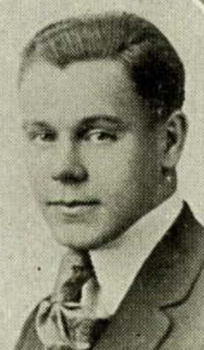 Three quarter profile of head and neck of young man wearing suit and tie.