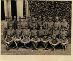 Photo of 28 men in uniform wearing campaign hats, arranged in three rows, the men in front sitting, the two rows behind standing.